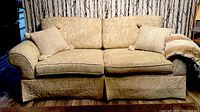 Front view of 2-seater fabric couch with cushions and throw blanket, showing upholstery pattern and overall shape.