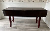 Dining table in closed position, showcasing the compact size with leafs folded down.