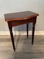 Wooden side table showing scalloped top surface, turned legs, and polished finish.