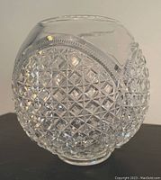 Clear glass vase or bowl with textured diamond cut pattern on sides and smooth top rim, photographed on neutral surface.