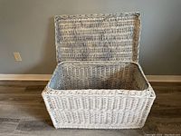 Open top view showing interior of white wicker storage chest with hinged lid.