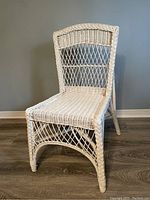 Front view of white wicker chair without cushions showing woven wicker seat and back frame.