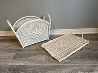 White wicker magazine rack and matching rectangular tray on wooden floor against gray wall