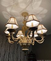 Ceiling view of beige chandelier with five fabric lampshades creating light patterns on the ceiling.