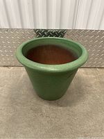 Side view of the green ceramic flower pot showing the textured exterior and rounded lip.