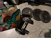 Image showing adjustable dumbbell with spin-lock collars and two larger weight plates on floor.