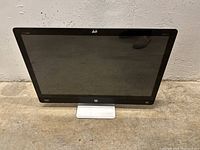 Front view of HP Envy 27 all-in-one desktop computer showing black bezel screen and silver stand, device standing on concrete floor.