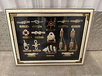 Front view of framed nautical knot display with ship models and pulley blocks.