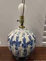 Full view of vintage ceramic lamp with blue floral pattern, brass light fixture, and clear glass base