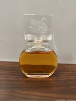 Front view of vintage Vanderbilt perfume bottle with amber liquid and swan embossed cap