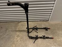 Full body image of black metal trailer hitch bike rack with two arms for holding bikes.