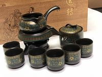 Complete 9-piece ceramic Chinese Gongfu tea set displayed on surface: teapot on warmer, kettle, and seven tea cups decorated with crane and floral patterns.