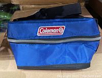 Blue Coleman collapsible cooler with black adjustable shoulder strap and handle, showing Coleman logo on front.