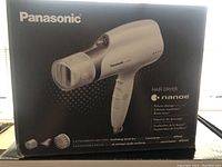 Front view of Panasonic EH-NA67 hair dryer box showing product image and features like nanoe technology and included attachments.