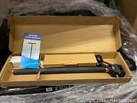 Fully assembled pump in packaging box with instruction manual beside it.