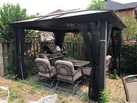Gazebo structure with outdoor dining chairs and grill beneath