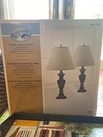 Photo of boxed 2-pack Hampton Bay table lamp set with product details including dark bronze finish and golden brown fabric shades
