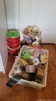 Photo showing multiple unopened and opened ribbon spools stacked and in a plastic basket with various ribbons visible