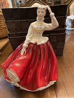 Front view of Royal Doulton Gail porcelain figurine showing detailed face, white jacket with yellow accents, and red full skirt.