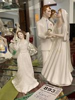 Both Royal Doulton figurines displayed together on glass shelf for size comparison and overview.