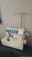 Full view of the white Simplicity serger machine with thread stand and control dials.