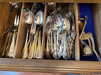 Over 50 pieces of Wm. A. Rogers silverware displayed in wooden divided drawer, showing two distinct handle patterns and assortment of forks, spoons, and other utensils