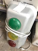 Full view of the plastic display stop light showing the green, yellow, and red lenses with power cord wrapped around it.