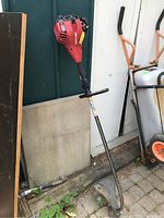 Full view of the Homelite red gas powered weed trimmer with shaft and trimmer guard.