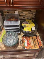 Overview image showing all items including T-fal wok, stack of non-stick cake pans, glass bowls, and griddle on granite counter.