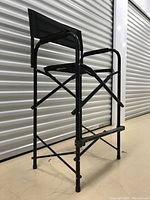 Side angle showing the black metal frame, fabric seat and backrest, footrest, and overall structure of the director's chair.