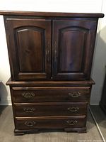 Front view of the mahogany dresser showing closed front doors and three lower drawers with brass handles.