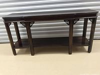 Front view of mahogany entrance table showing detailed corner accents and leg structure with lower shelf.