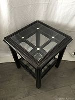 Front and top angled view showing the square glass top with wooden frame and the support structure below.