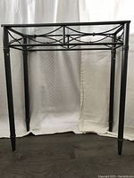 Side view of the silver narrow entrance table showing decorative crossbar and tapered legs on dark flooring against white background.