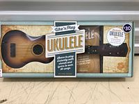 Front view of the ukulele in original box with kit accessories visible.