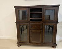 Photo of dark wood dining storage unit with glass doors and multiple storage compartments.