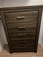 Front view of the wooden chest showing five drawers with metal handles.