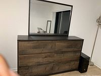 Front view of wooden dresser with mirror showing six drawers with rustic wood finish drawer fronts and darker wood frame.
