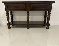 Front view of wooden hallway table showing two drawers and turned legs with lower shelf.
