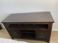 Top-side angle view showing storage shelves and glass doors of the wooden TV stand.