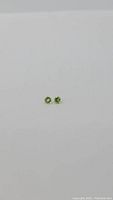 Two natural apple green peridot gemstones shown side by side on a white background, highlighting their round cut and matching color with clarity
