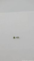 Natural bright green tourmaline emerald cut gemstone on a plain white background, showing size and clarity.