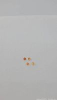 Four small round orange carnelian gemstones laid out on white background.