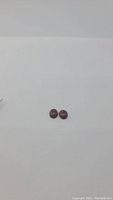 Pair of espresso-colored pietersite cabochon gemstones placed on white background, showing front sides.