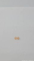 Pair of small oval peach moonstone cabochon gemstones placed side by side on a plain white background, showing their shape and color from a top-down view.
