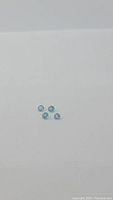 Four natural paraiba blue apatite gemstones placed on a white background viewed from slightly above.