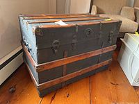 Front and side view of antique steamer trunk showing metal hardware, wooden slats, and general condition