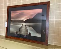 Full view of the framed photograph showing dock and mountains with visible scratches on frame