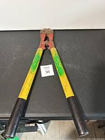Full view of bolt cutters showing long yellow and green handles and black rubber grips