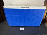 Blue Coleman cooler front view showing blue body and white lid with handle latch.